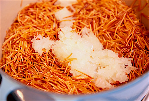 Add grated onion into browned Barilla cut spaghetti