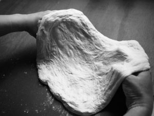 pizza dough draped over hands