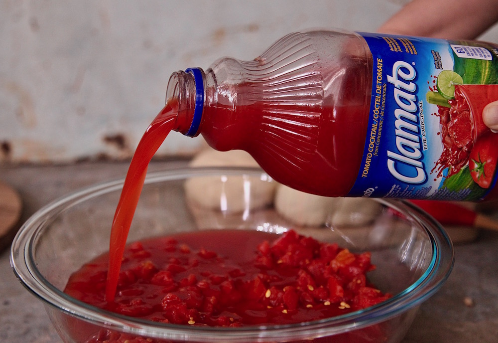 Pouring Clamato over tomatoes